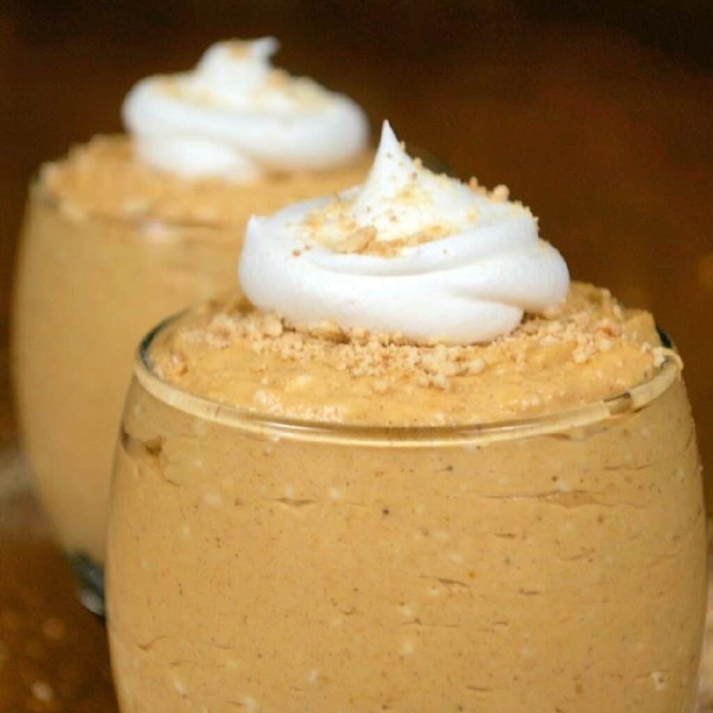 Close up of No Bake Pumpkin Cheesecake Cups with whipped cream on top.