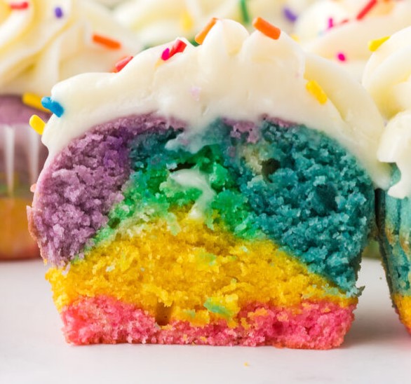 A tie dye cupcake cut in half to show the inside swirl of colors.
