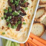 Cheesy Bacon Dip in white bowl with crackers for dipping.