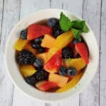 Top down view of fruit salad with honey lime dressing in a white bowl.