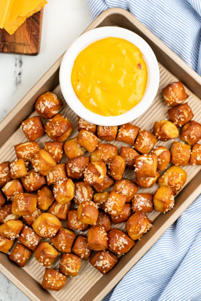 Golden brown pretzel bites and cheese dip on a sheet pan.