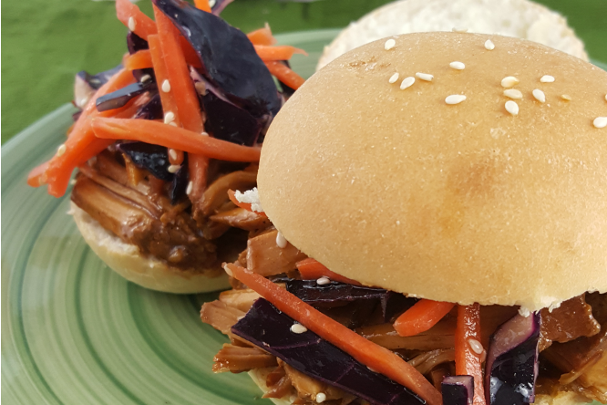 Close up of pulled pork sliders with slaw on a green plate.