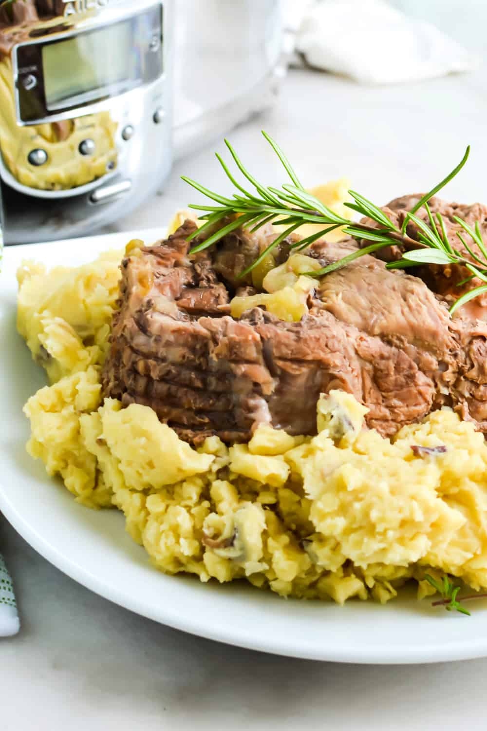 Slow cooker pork roast on a bed of mashed potatoes.