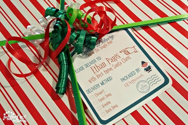 A North Pole Printable Gift Tag on a red and white christmas gift, secured with festive ribbon.