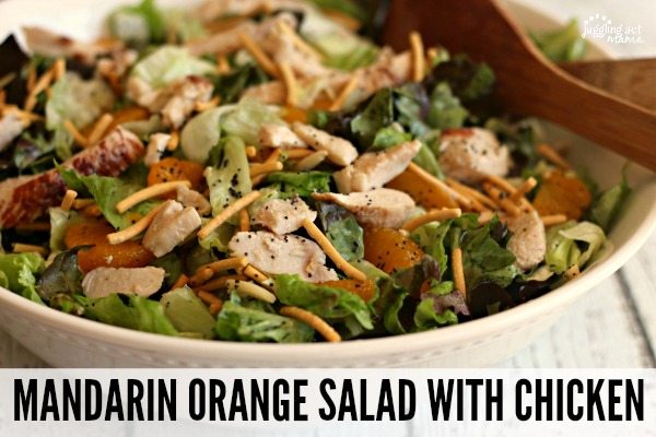 A close up of a large bowl filled with Mandarin Orange Salad including Chow Mein noodles, slivered almonds, and chicken on romaine and red leaf lettuce topped with a poppyseed dressing.