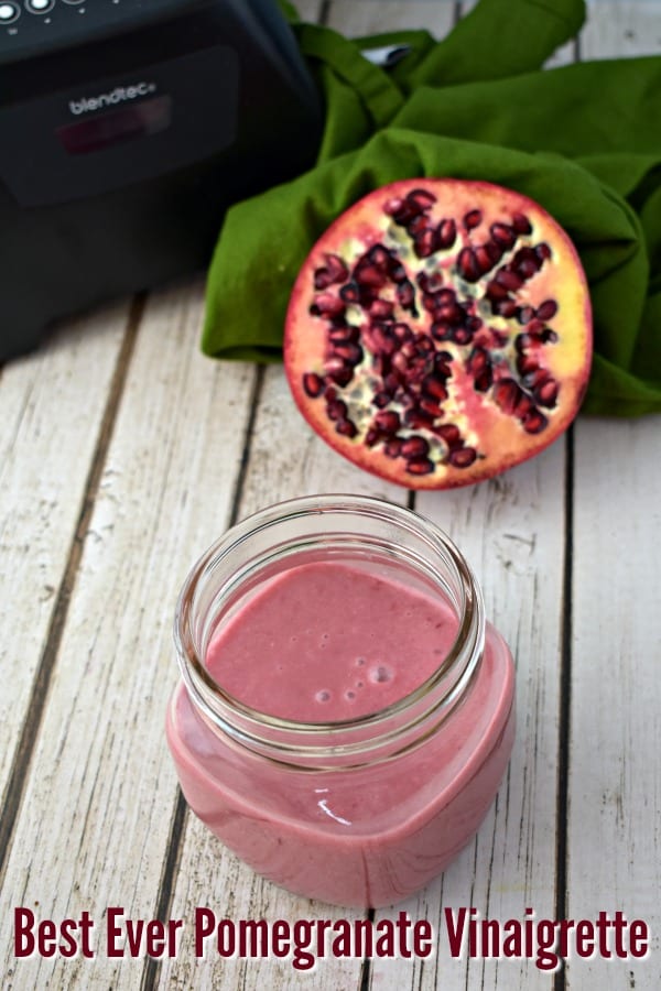 jar of pomegranate vinaigrette with half of a pomegranate in the background