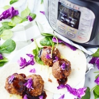 Korean Meatballs in a soft taco shell with purple cabbage. An Instant Pot Pressure cooker is seen in the background.