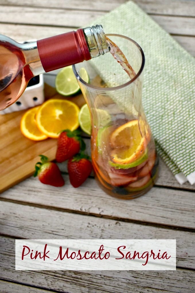 A glass carafe with fruit on the bottom being filled with Moscato wine.