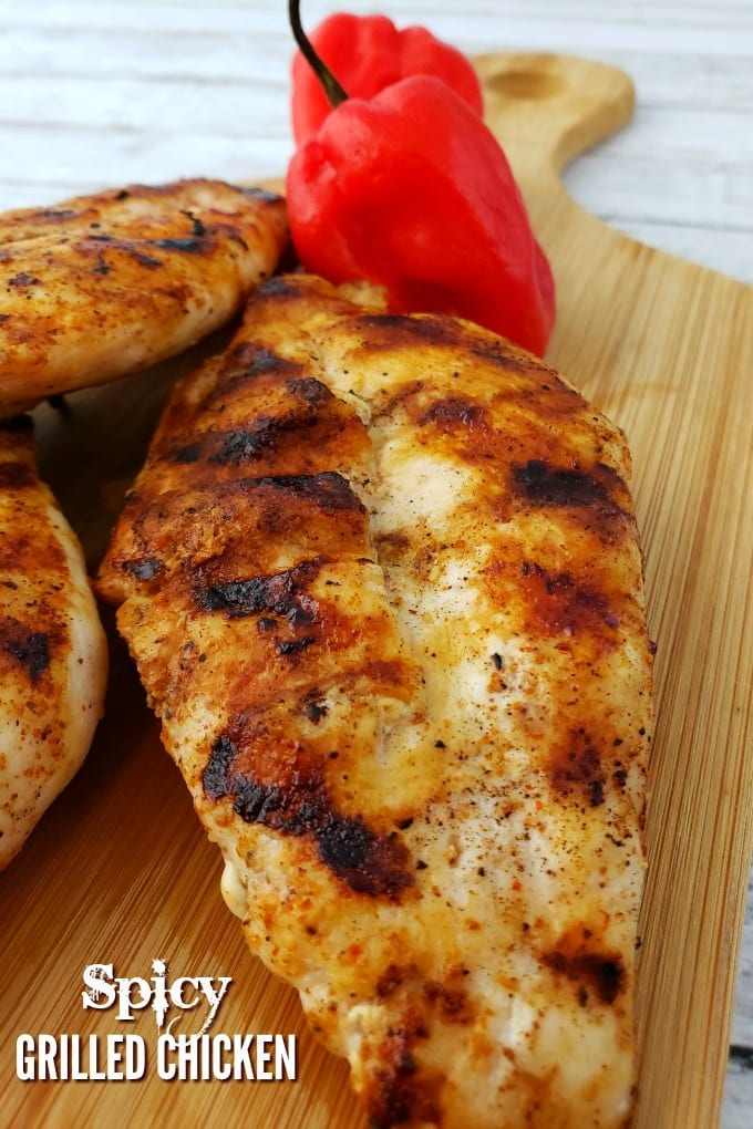 Spicy Grilled Chicken on a small cutting board with a couple of habanero peppers