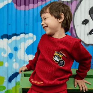 young boy in a red shirt against a graffiti background