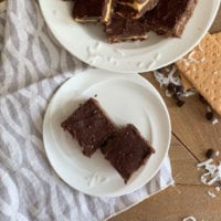 nanaimo bars on white plate with cloth napkin wood table