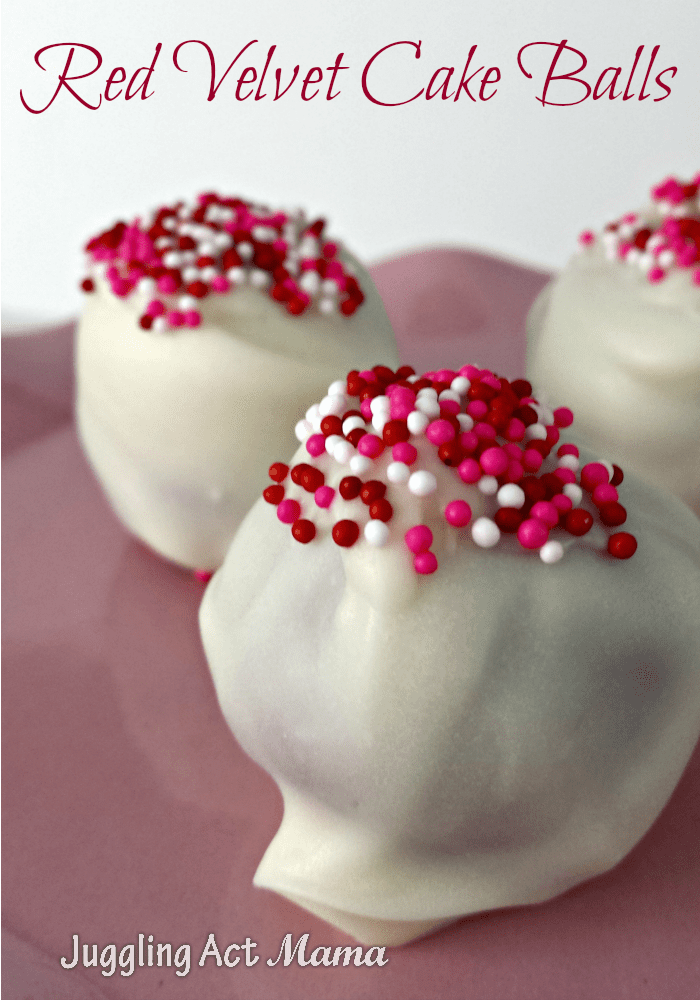 A red Velvet Cake Ball covered with white chocolate sits on a pink plate.