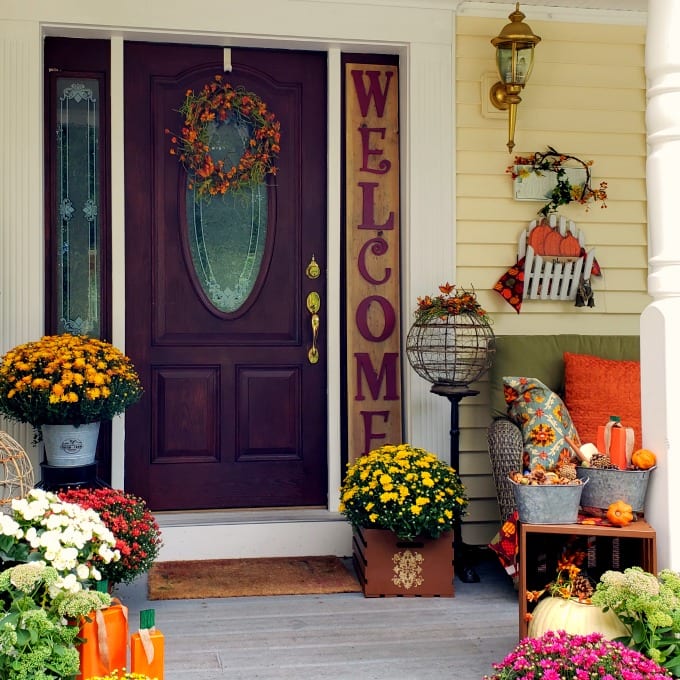 Fall Porch Decorating Ideas - a porch and front door decorated for Fall with colorful mums, pumpkins and other decorations.