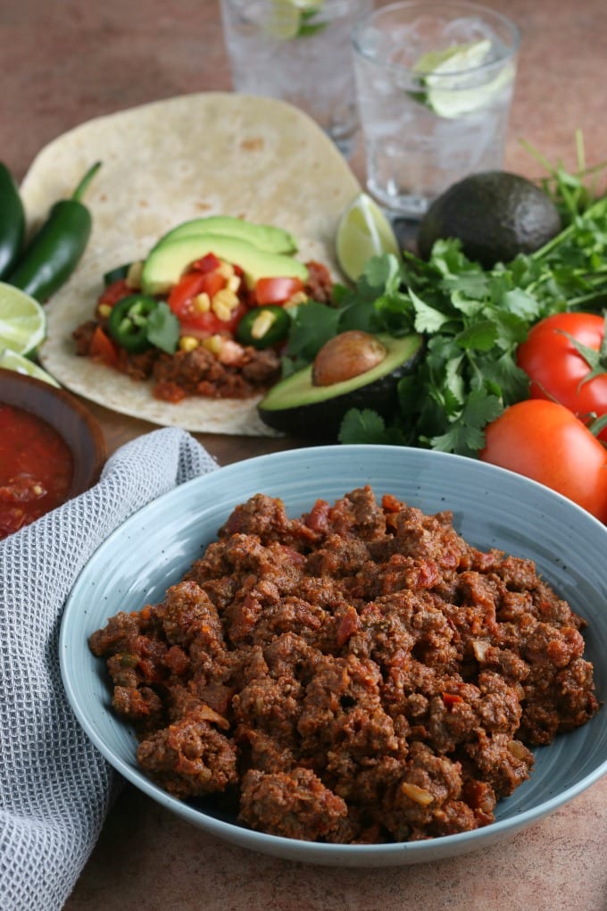 ground beef taco meat in a bowl surrounded by taco ingredients.