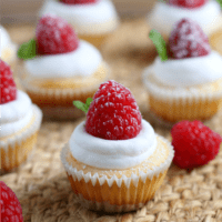 Close up of easy mini cheesecakes topped with whipped cream, raspberries and mint leaves.