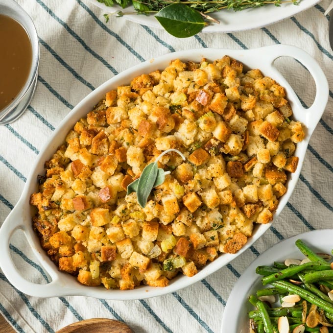 Square, top down image of cornbread sausage stuffing in a white baking dish.