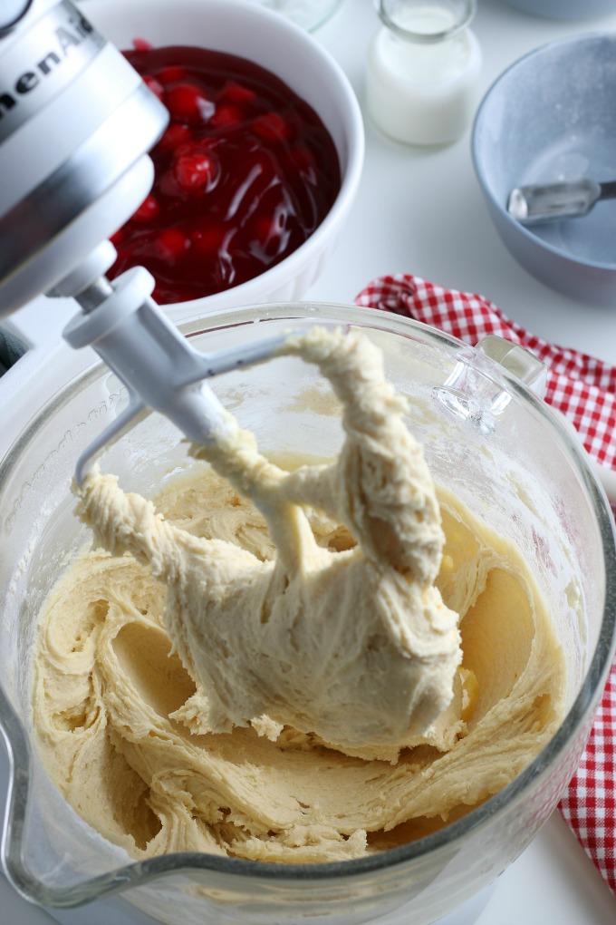 Cherry Pie Bars Recipe - Stand mixer beater attachment in a glass mixing bowl. Covered in batter.