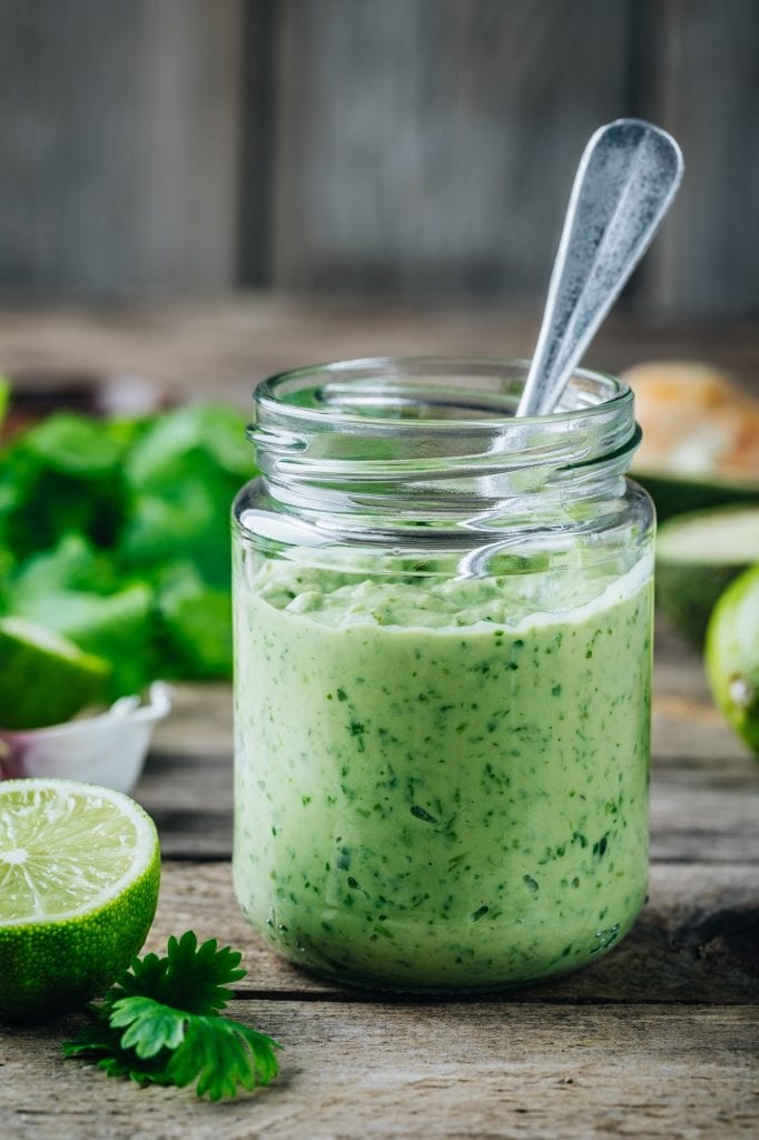 Lime Mayonnaise with lime and cilantro in a glass jar on a rustic background