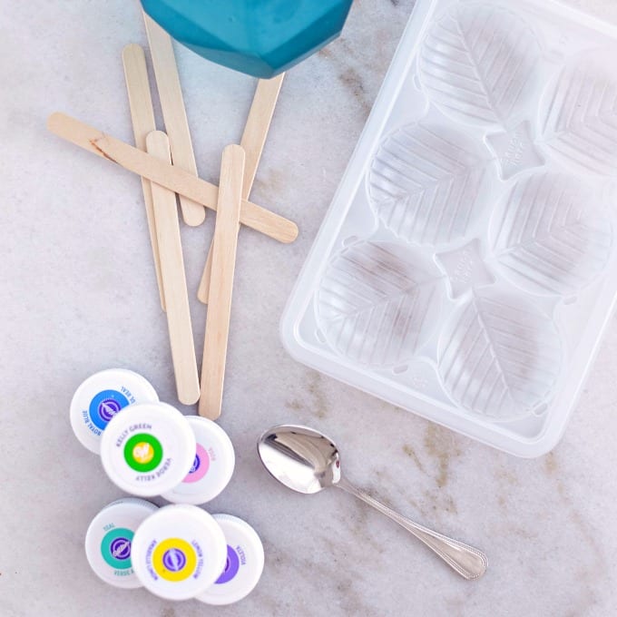 close up of an ice cube tray, craft sticks and food coloring to make colored ice cubes for painting