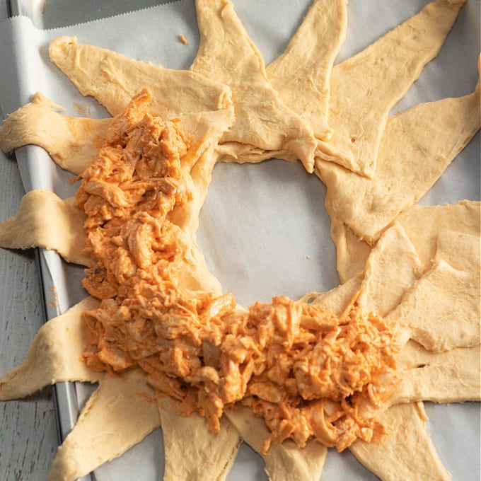 How to Make a Buffalo Chicken Crescent Ring - process photo showing how to lay out the crescent rolls to make the crescent roll buffalo chicken ring and then add the buffalo chicken dip filling.