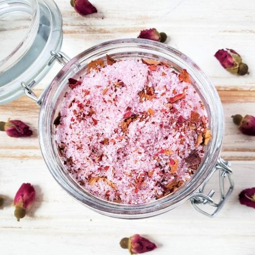Close up, top down image of rose bath salts in a glass jar with airtight lid.