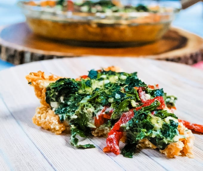 Slice of spinach and sweet potato quiche on a wood platter.