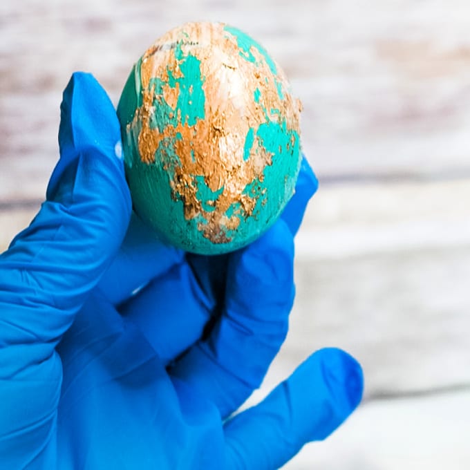 close up of a gloved hand holding an Easter egg with Gold Leaf