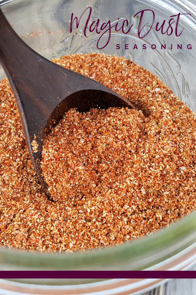 Close up image of a wooden spoon in a jar of magic dust rub seasoning mix.