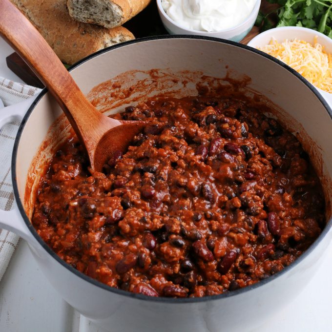 Chili in a large pot with a wooden spoon.