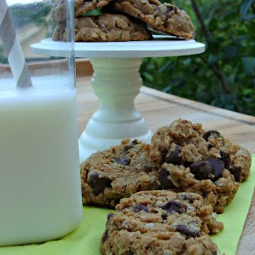 Chocolate chip peanut butter oatmeal cookies on a green napkin with a glass of milk.