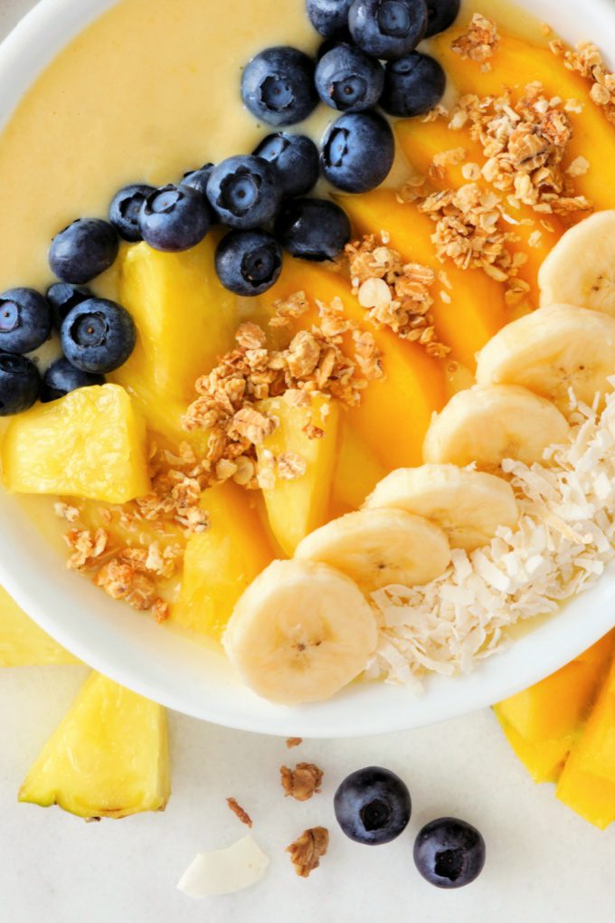 Top down view of a pineapple smoothie bowl topped with fresh blueberries, pineapple and bananas.