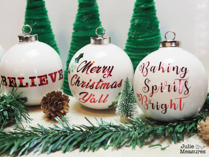 Three white Christmas ornaments with metallic vinyl sayings.