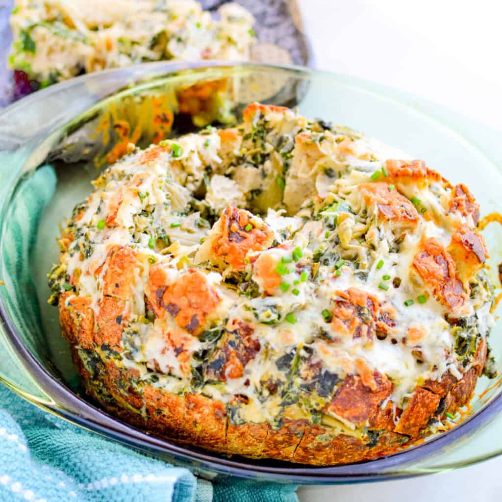 Close up image of spinach and artichoke pull apart bread in a glass dish.