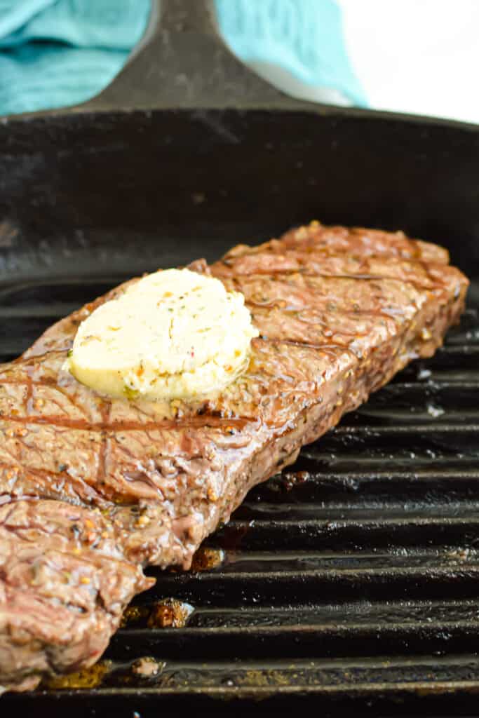 Broiled New York Strip Steak in a grill pan with garlic herb butter.