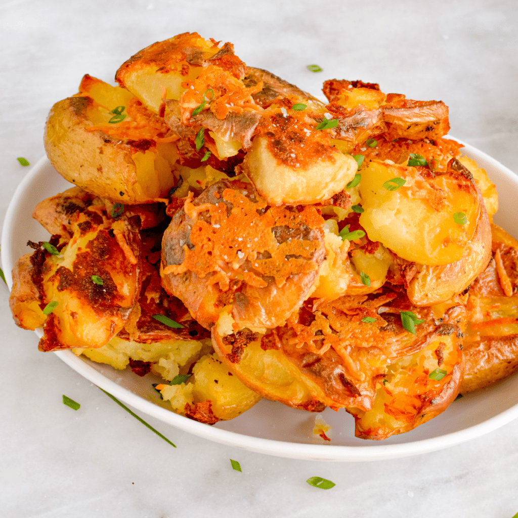 Crispy Smashed Potatoes piled high in a white serving dish.