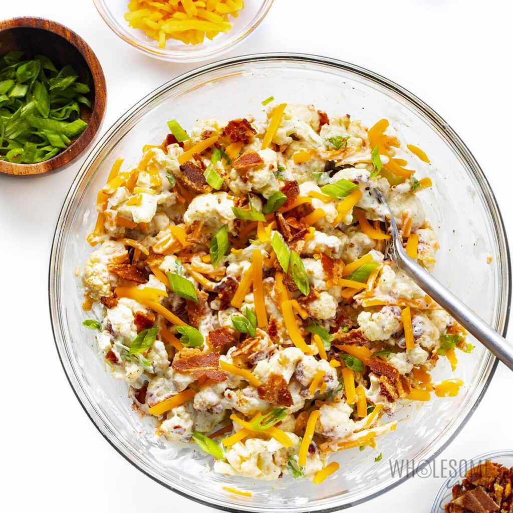 Top down view of a glass bowl filled with loaded cauliflower salad. 