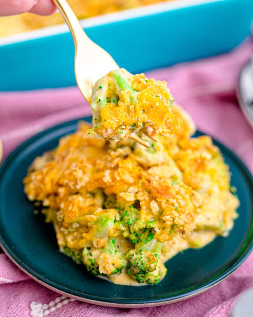 Velveeta broccoli casserole on a fork above a plate.