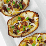 Top down view of potato skins with bacon and cheese on a white plate.