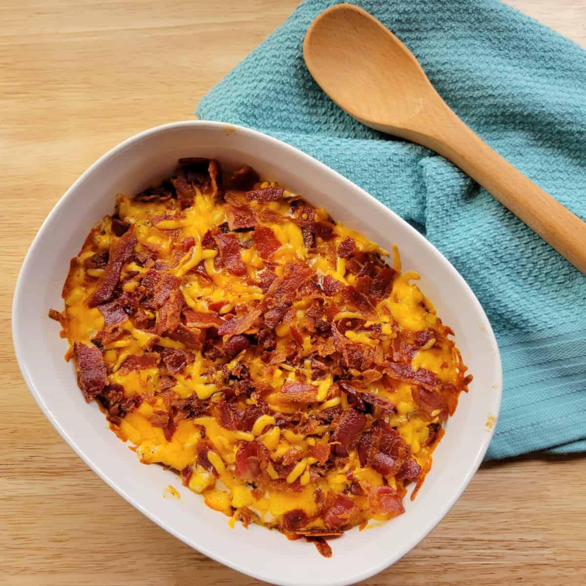Close up of Cowboy Corn Casserole topped with bacon in a white baking dish.