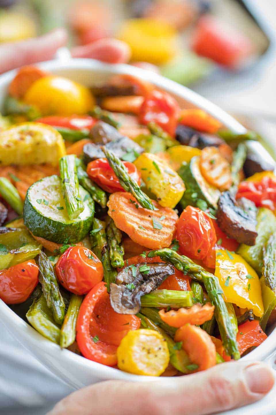 Close up of a bowl of Oven Roasted Vegetables being held.