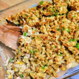 Close up of Chicken Stuffing Bake in a casserole dish with a wooden spoon.