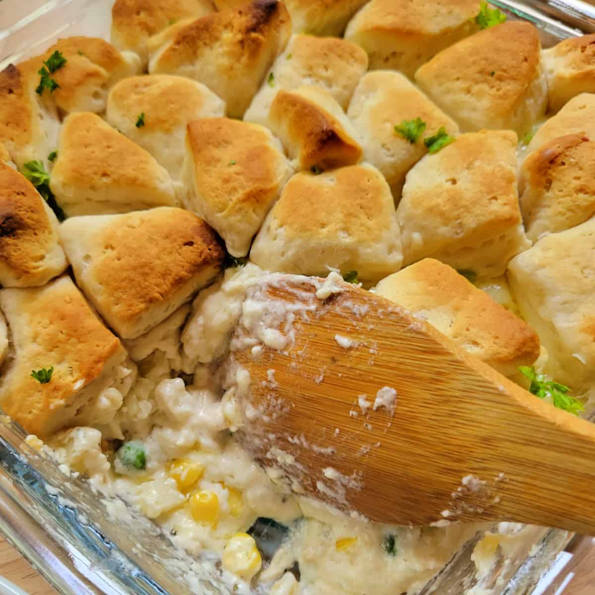 Close up of Chicken Bubble Biscuit Casserole with a wooden spoon.
