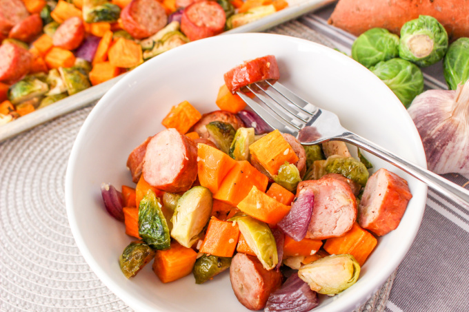 Chicken Apple Sausage Sheet Pan Dinner in a white bowl with a fork.