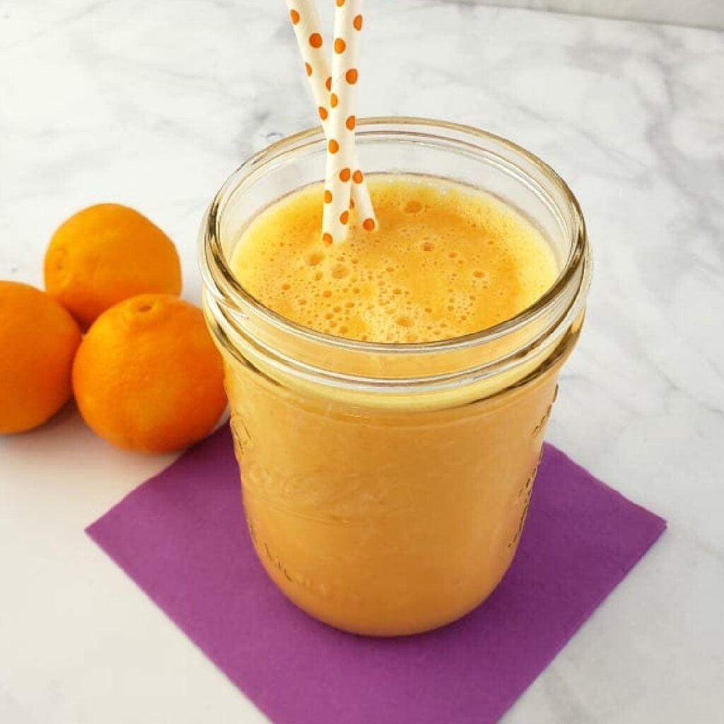 Close up of a Clementine Smoothie in a mason jar with two polka dot straws.