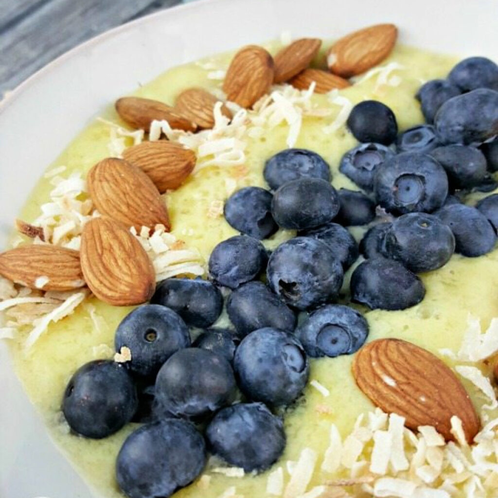 Close up of fresh blueberries, whole almonds, and toasted coconut on a Banana Blueberry Smoothie Bowl.