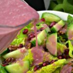 Close up of Pomegranate Dressing being drizzled onto a salad.