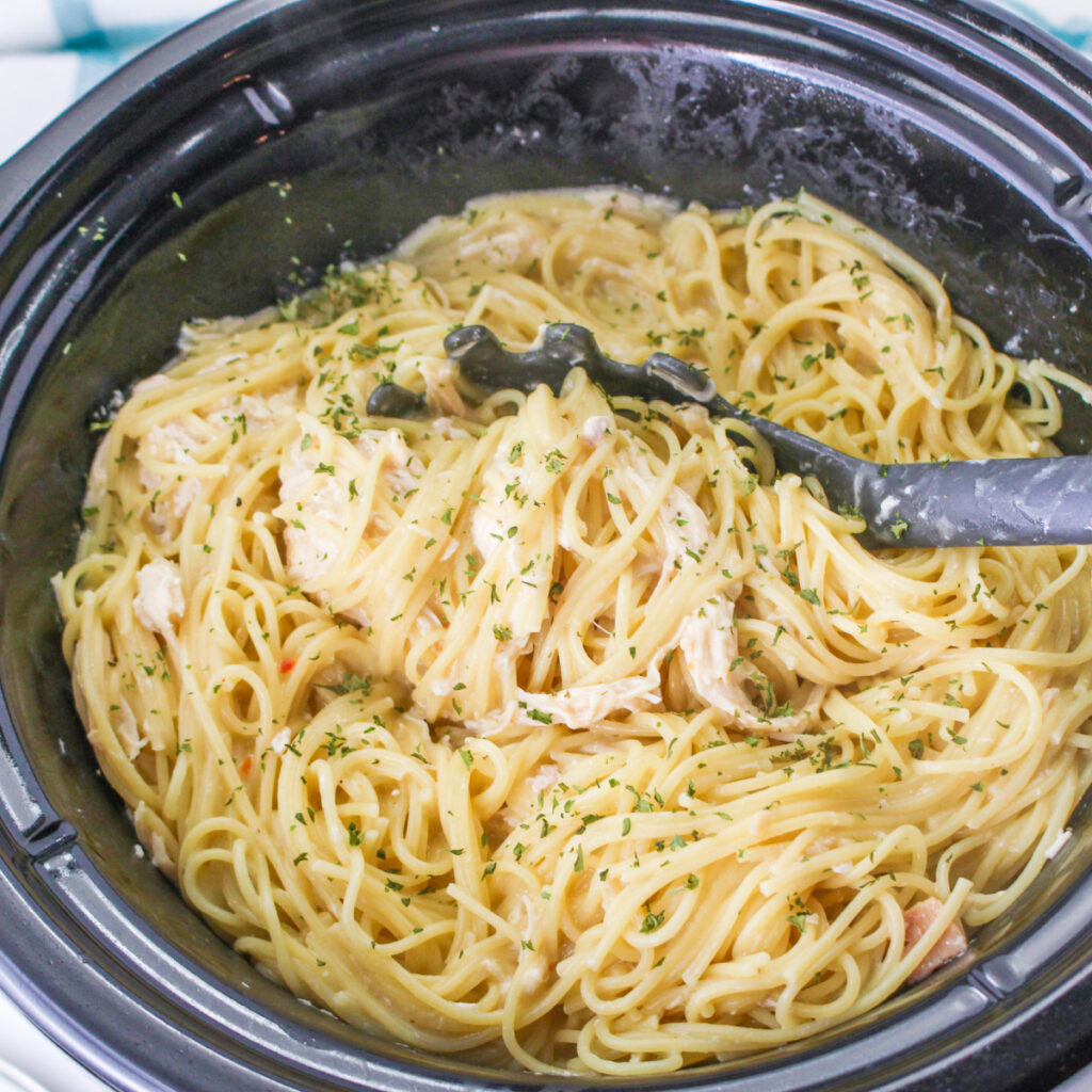 Slow Cooker Angel Chicken Pasta in a slow cooker with a serving spoon.