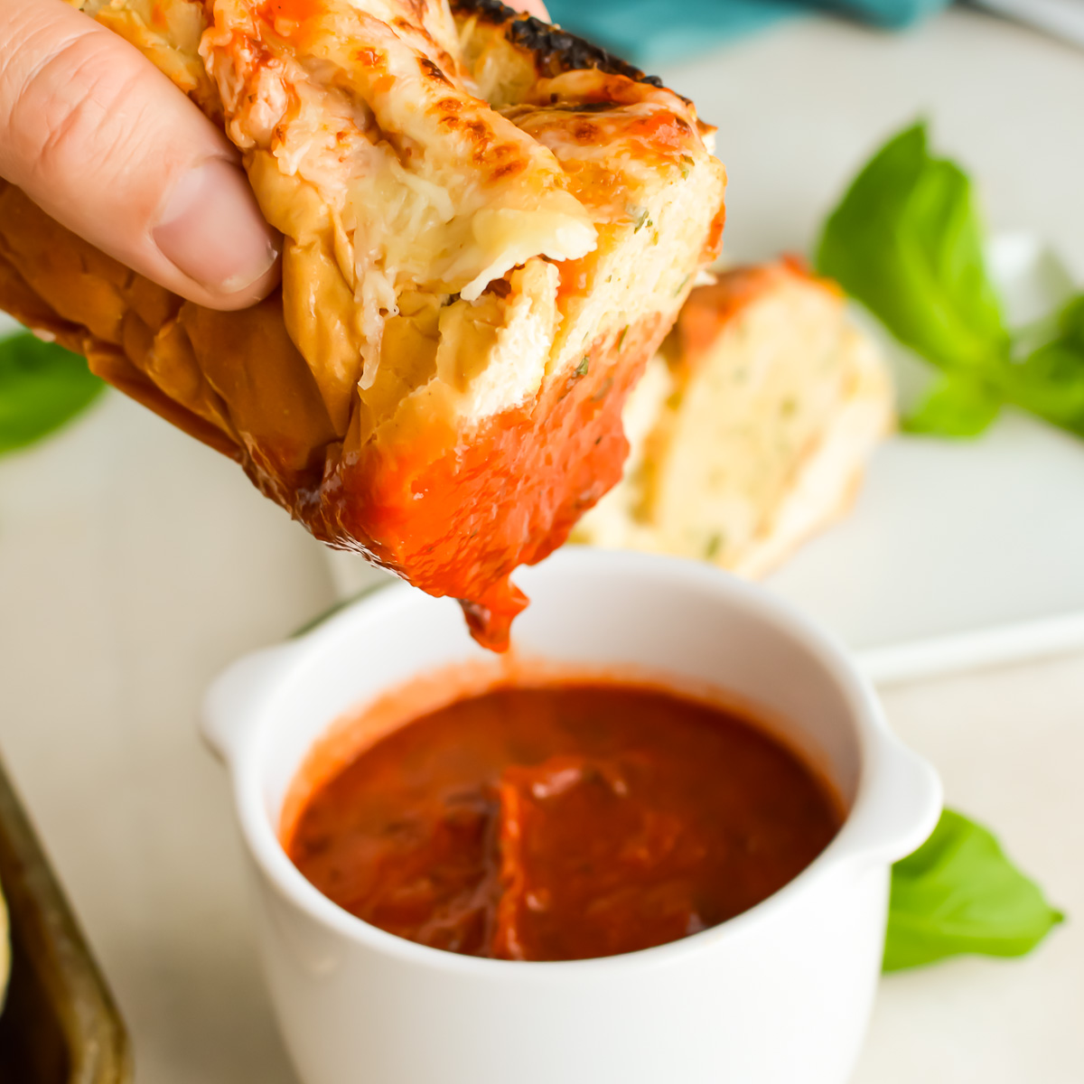Hand dipping a Chicken Meatball Sub into tomato sauce.