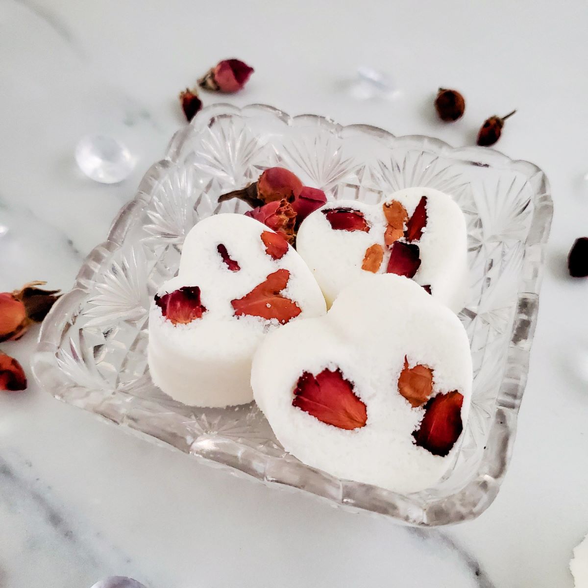 Rose Petal Bath Bombs in a glass dish on a counter top.