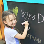 Little girl drawing on an Outdoor Chalkboard.